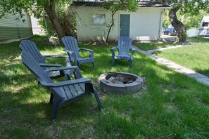 A backyard with three Adirondack chairs, a fire pit, and a small shed. - Quaint cabin at the Lake (Sylvan Lake)