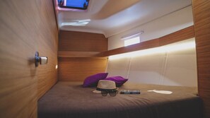 A compact room with a bunk bed, a television mounted on the ceiling, and a small window. - Sun-Kissed Sailing Adventure in Split, Croatia (Split)