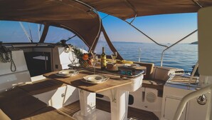 A boat's dining area with a table set for two, a bottle of wine, and a fruit bowl. - Sun-Kissed Sailing Adventure in Split, Croatia (Split)