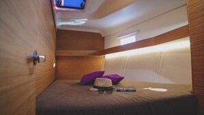 A compact room with a bunk bed, a television mounted on the ceiling, and a small window. - Sun-Kissed Sailing Adventure in Split, Croatia (Split)