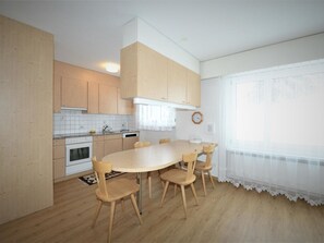 A kitchen with wooden cabinets, a white stove, and a dining table with chairs. - Uehlinger Seegarten Wirz Appartement/Fewo,   Wohnung Seegarten Wirz by Interhome (Lenzerheide)