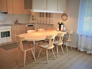 A kitchen with a wooden table and chairs, a clock on the wall, and a window with sheer curtains. - Uehlinger Seegarten Wirz Appartement/Fewo,   Wohnung Seegarten Wirz by Interhome (Lenzerheide)