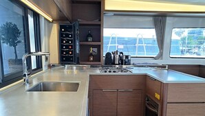 A modern kitchen with stainless steel appliances, wooden cabinets, and a wine cooler. - Sun-Kissed Sailing Adventure in Islas Sarónicas (Piraeus)