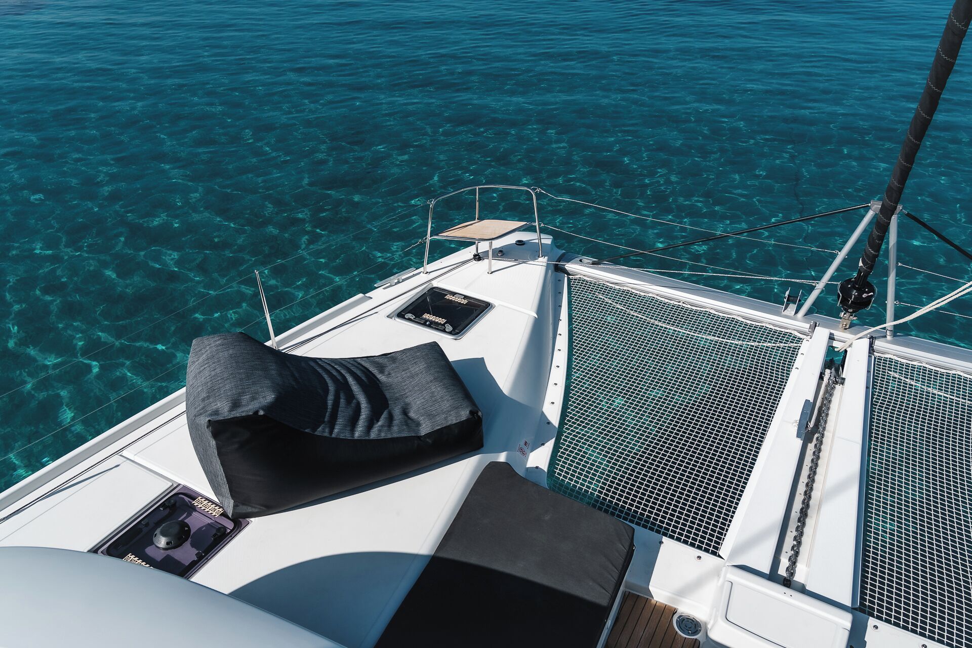 A boat deck with a cushioned seating area, a control panel, and a clear view of the turquoise water.