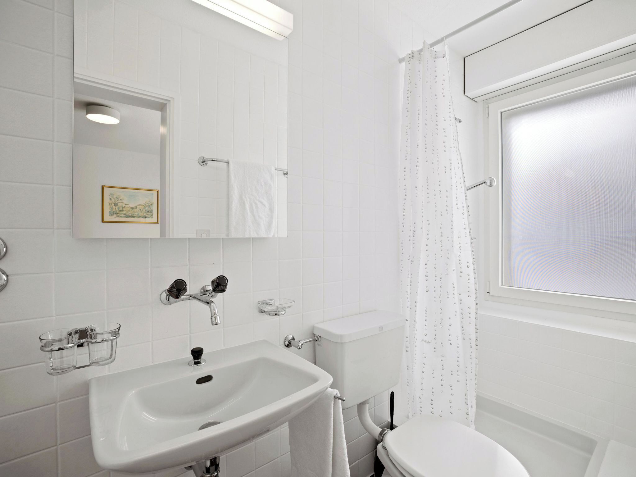 Ein Badezimmer mit einem weißen Waschbecken, einer Toilette und einer Duschkabine.