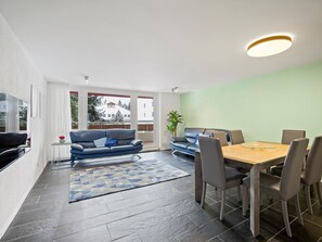 A modern living room with a sofa, a dining table with chairs, a coffee table, a rug, and a potted plant. - Nr.14 Haus Astoria Appartement/Fewo Nr.14 Haus Astoria by Interhome (Lenzerheide)