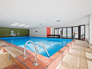 An indoor swimming pool with a clear view of the pool area, a tiled wall, and a bench. - Nr.14 Haus Astoria Appartement/Fewo Nr.14 Haus Astoria by Interhome (Lenzerheide)
