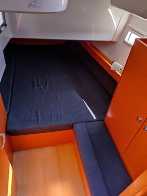 Ein kompakter, abgeschlossener Schlafbereich mit gepolstertem Bett, einem kleinen Fenster und einem Stauraumschrank.