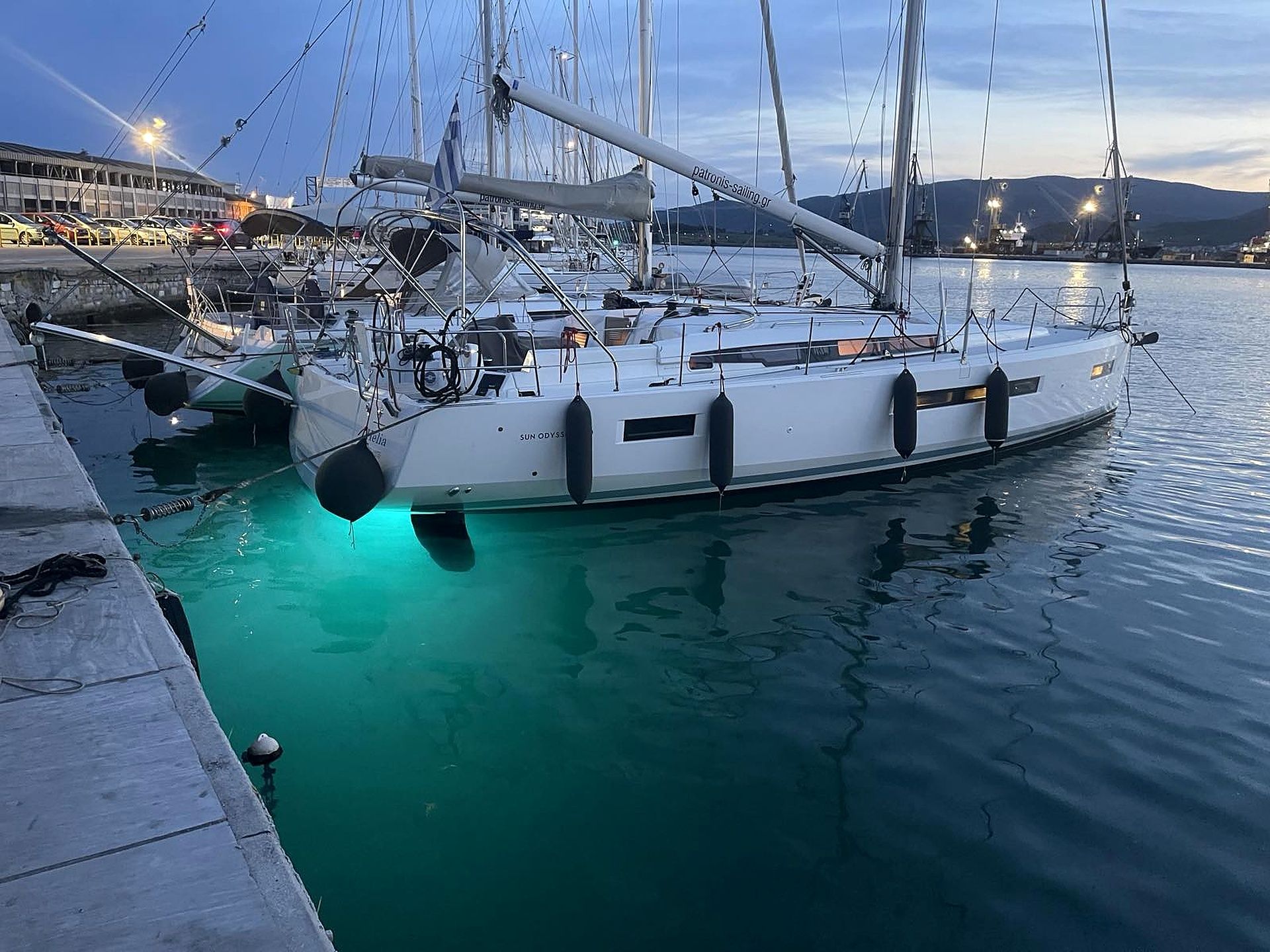 Eine Segelyacht liegt im Hafen festgemacht, mit freiem Blick auf das Wasser und einer Stadtlandschaft im Hintergrund.