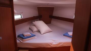 A compact cabin with a single bed, a small bench, and a skylight.