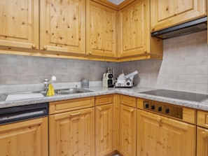 A kitchen with wooden cabinets, a granite countertop, a dishwasher, and a stove. - Casa Hermi Appartement/Fewo 2.5 Zimmerwohnung by Interhome (Churwalden)