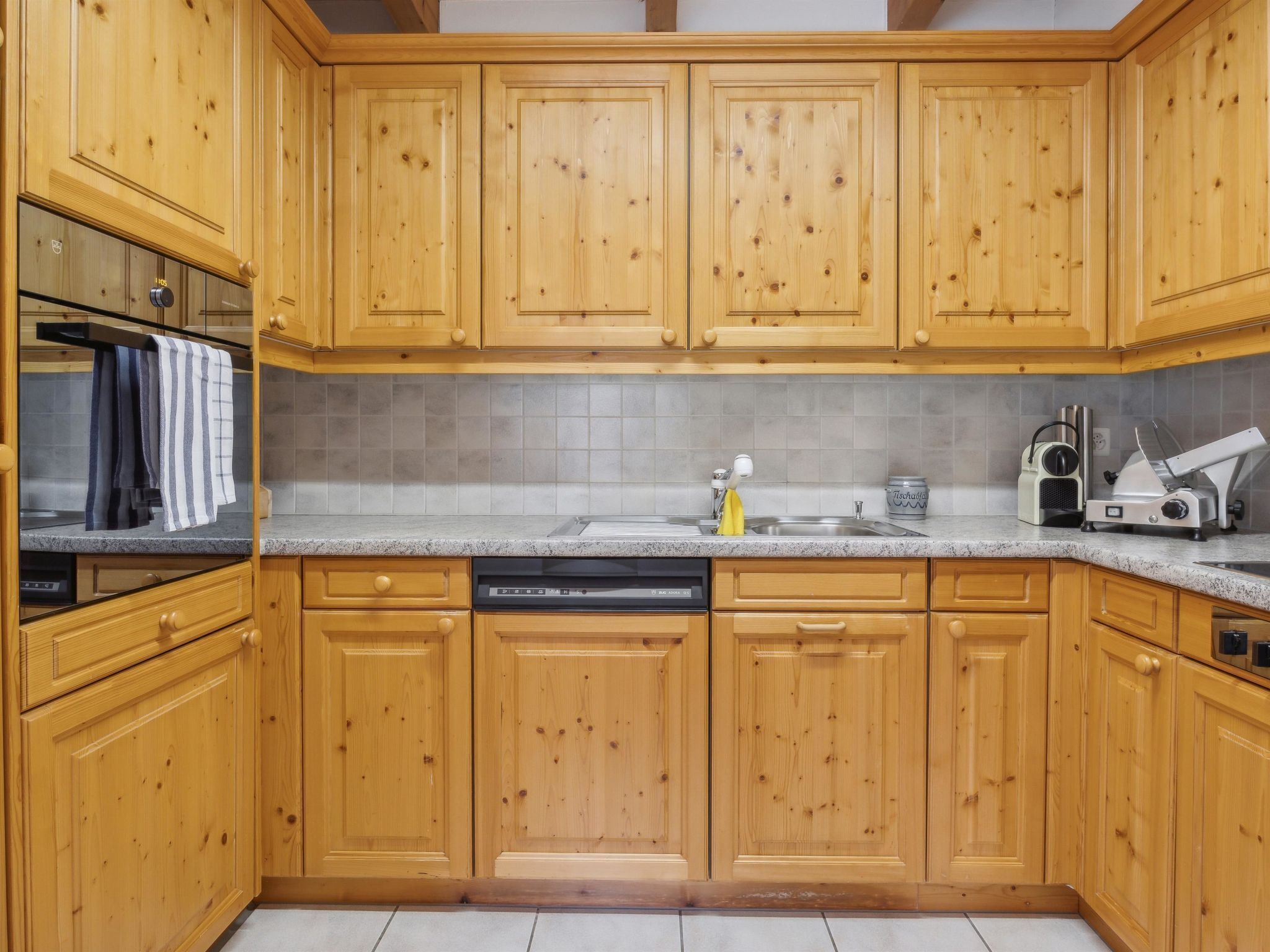 A kitchen with wooden cabinets, a dishwasher, a sink, and a stove.