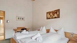 Un letto rifatto con lenzuola e asciugamani bianchi, una testiera in legno, un comodino e un mappamondo fissato al muro.