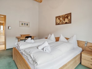 A neatly made bed with white linens and towels, a wooden headboard, a bedside table, and a wall-mounted globe. - Casa Hermi Appartement/Fewo 2.5 Zimmerwohnung by Interhome (Churwalden)