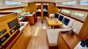 Een ruimtelijk ingericht bootinterieur met een keuken, eethoek en zitplaatsen.