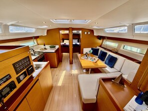 A compact boat interior with a kitchen, dining area, and seating. - Sun-Kissed Sailing Adventure in the Stunning Islas Cícladas (Paros)