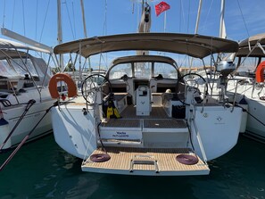 A sailboat docked at a marina with a covered deck, a steering wheel, and a life preserver.