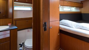 Un intérieur de camping-car compact, avec un revêtement en bois, une petite salle de bain et un lit doté d’une tête de lit.