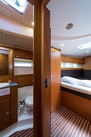 Ein kompaktes Wohnmobil-Interieur mit Holzvertäfelung, einem kleinen Badezimmer und einem Bett mit Kopfteil.