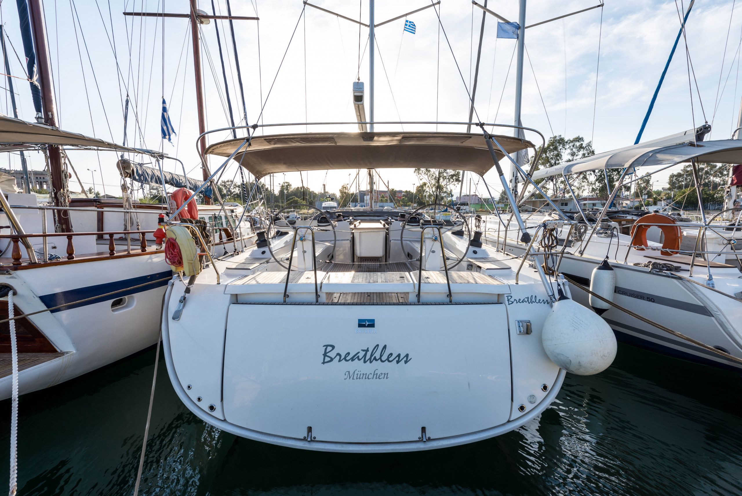 Eine Segelyacht liegt in einer Marina vor Anker, auf dem Bug steht 'Breathlen München'.
