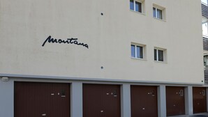 A building with a sign reading 'Montana' and a row of brown garage doors. - Haus Montana 1/1 Appartement/Fewo,   6-Bettwohnung by Interhome (Lenzerheide)