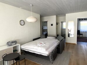 Ein Schlafzimmer mit Bett, Nachttischen, einer Uhr, einem Radio und einem Spiegel.