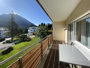 Ein Balkon mit Blick auf einen Berg, einem Holzzaun und einem Tisch.