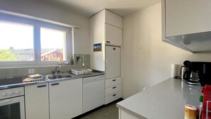 A kitchen with a window, a refrigerator, a stove, and a coffee maker. - Haus Montana 1/1 Appartement/Fewo,   6-Bettwohnung by Interhome (Lenzerheide)