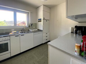 Eine Küche mit Fenster, Kühlschrank, Herd und Kaffeemaschine.