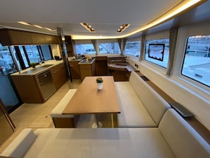 A compact kitchen with a dining area, a small table with a plant, and a bench. - Sun-Kissed Sailing Adventure in the Ionian Islands, Lefkada (Lefkada)