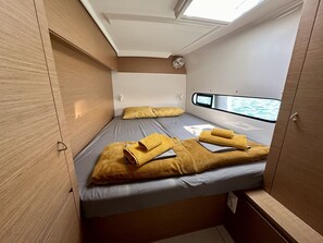 A compact cabin with a single bed, a small window, and a view of the water outside. - Sun-Kissed Sailing Adventure in Islas Baleares, Mallorca (Port de Pollença)