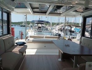 An interior view of a yacht with a dining area, a sofa, and a view of the marina with other boats. - Sibenik Sun-soaked Sailing: A Luxurious Croatian Voyage (Pirovac)