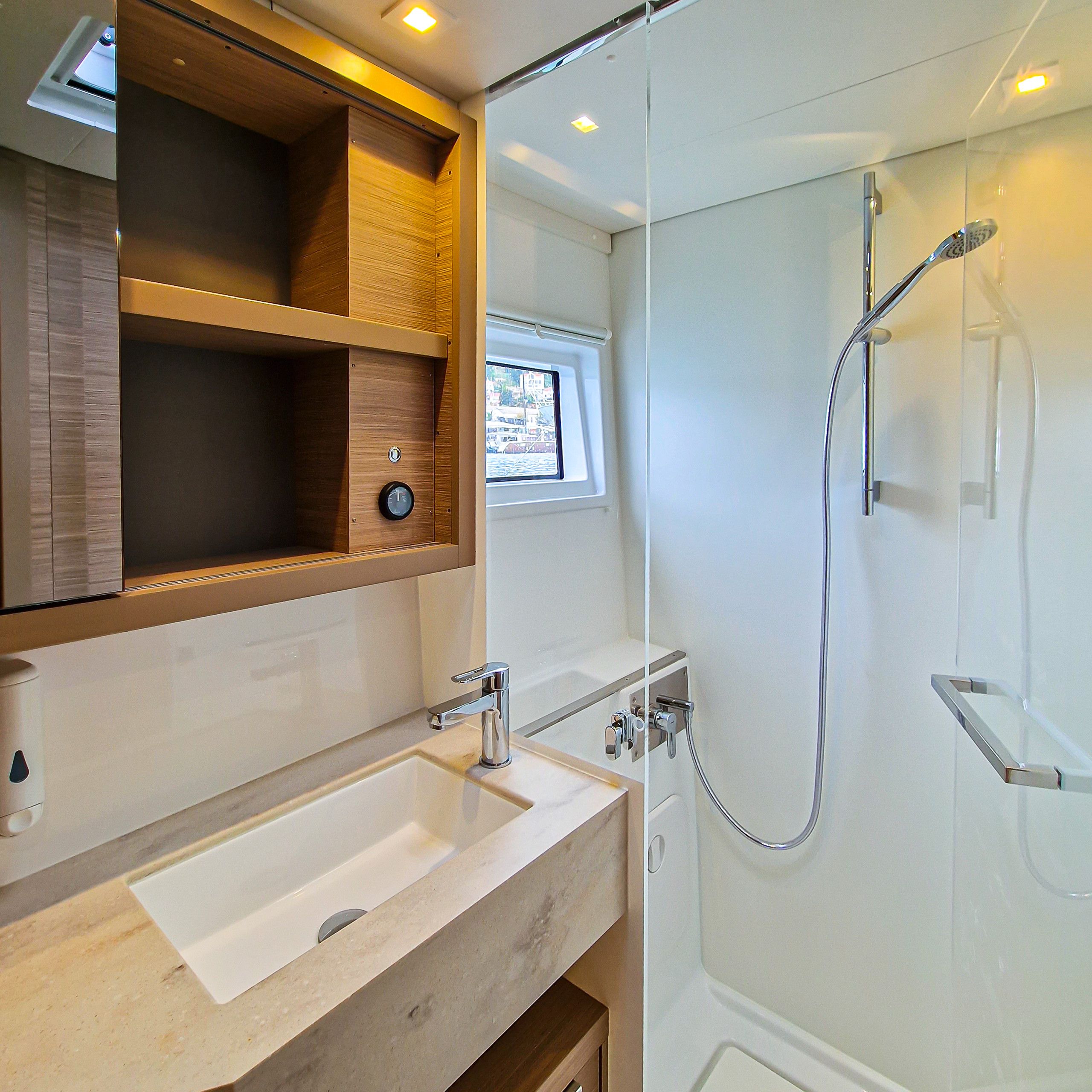 Une salle de bain avec un meuble-lavabo en bois, un évier, un miroir, une fenêtre et un espace douche.