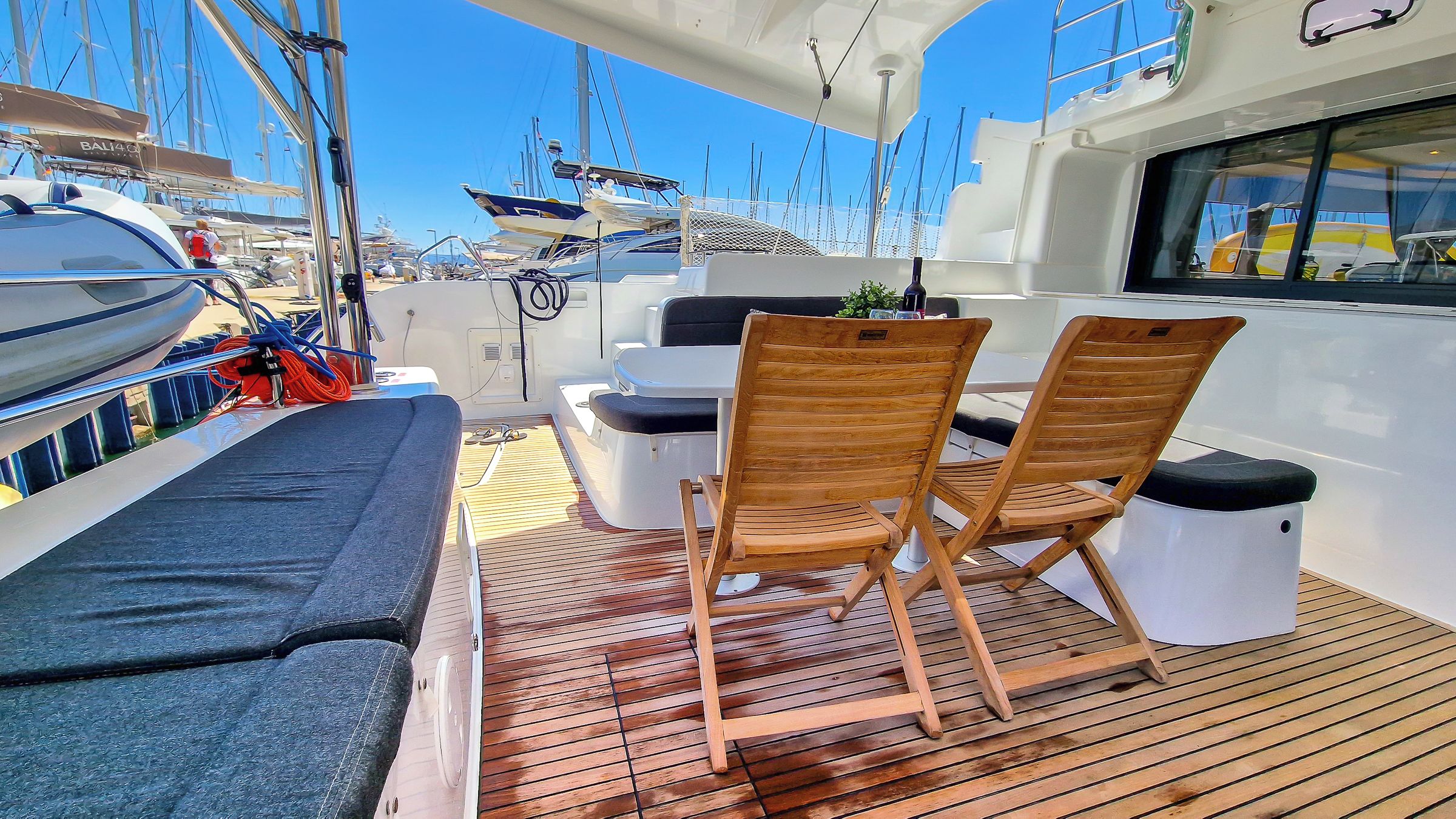 A deck with two wooden chairs, a small table, and a cushioned bench.