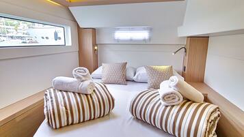 A modern hotel room with a large bed, striped pillows, a flat-screen TV, and a window with a view of the city.
