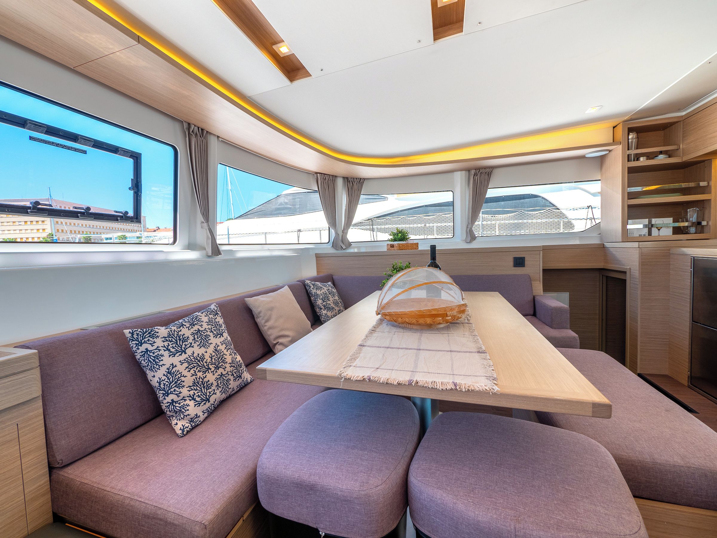 Ein modernes Interieur mit Sofa, Tisch und Küchenzeile, mit Blick durch große Fenster.