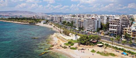 A coastal cityscape with a beach, buildings, and clear water.