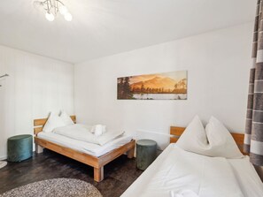 A hotel room with a bed, a bedside table, a chair, a painting on the wall, and a curtain. - Nr.08 Haus Sursilvana Appartement/Fewo,   Nr.08 Haus Sursilvana by Interhome (Lenzerheide)