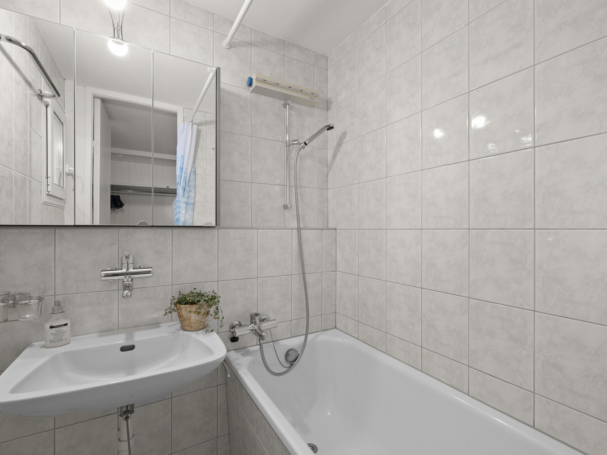 Une salle de bain moderne équipée d’une baignoire, d’un lavabo, d’un miroir et d’une douche.