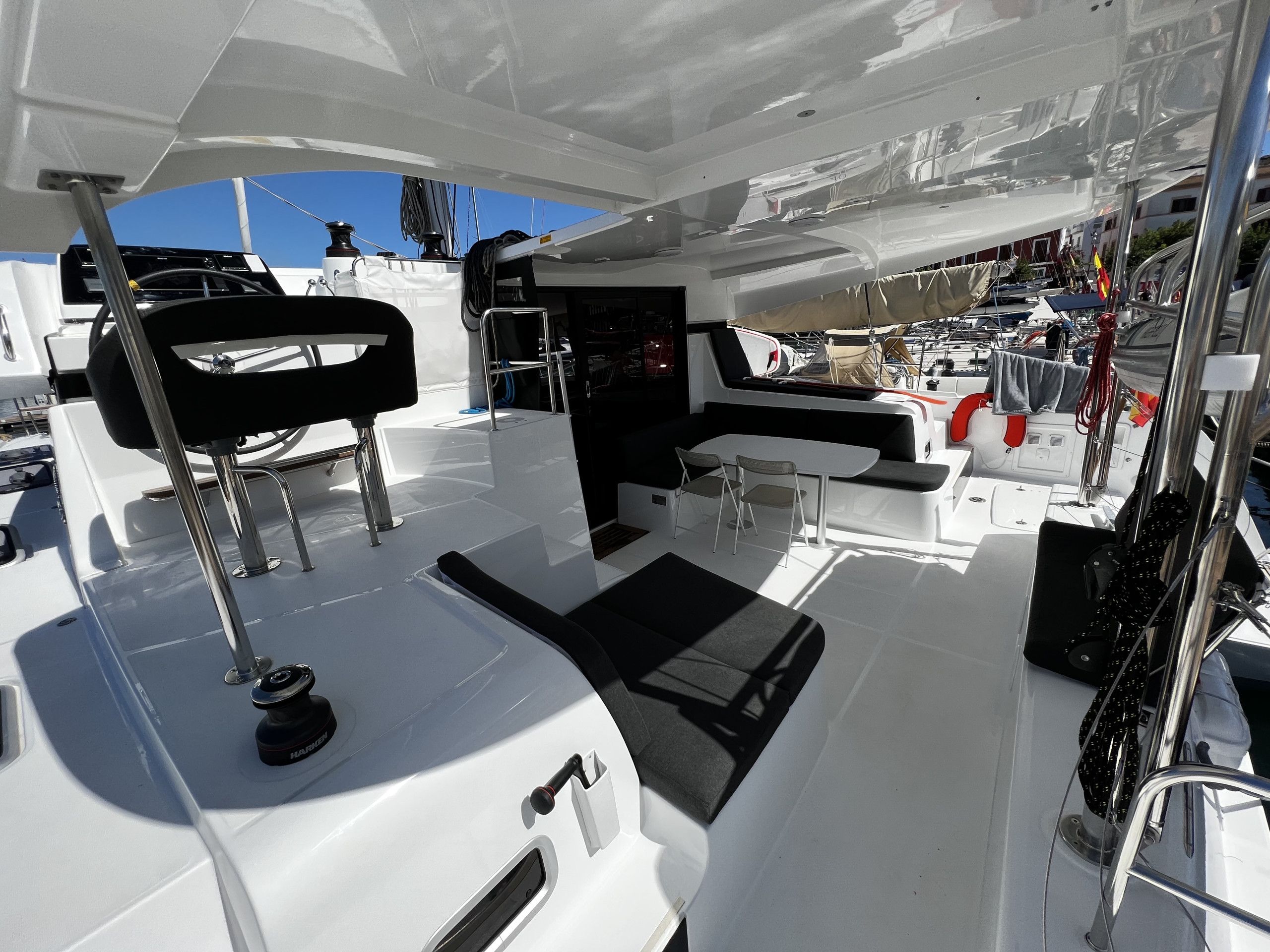 A boat's deck with a seating area, a steering wheel, and a control panel.