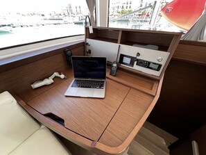A cabin with a laptop, a phone, and a radio on a wooden desk. - Sun-Kissed Sailing Adventure in the Majestic Islas Baleares (Ibiza / Eivissa)