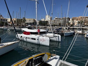 Un port de plaisance où sont amarrés de nombreux bateaux, un ciel dégagé et des bâtiments en arrière-plan.