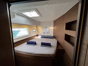 Un intérieur compact et bien éclairé, avec un lit, une lucarne et une petite fenêtre.