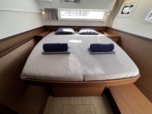 Un lit avec une tête de lit, des oreillers et une fenêtre avec des rideaux.