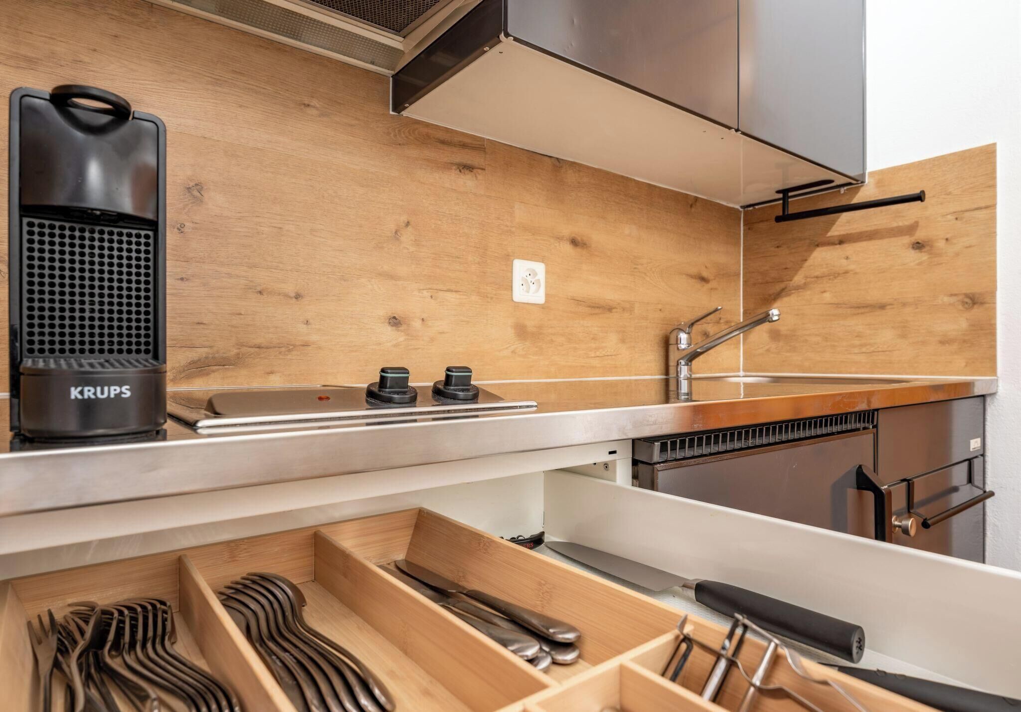 Una cocina moderna con armarios de madera, estufa empotrada y un lavamanos.