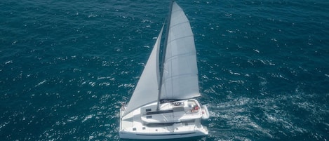 A sailboat with a white hull and a large sail, floating on a body of water.