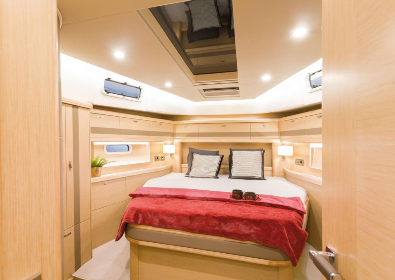 Een compacte, goed verlichte slaapkamer met een bed, nachtkastjes en een dakraam.