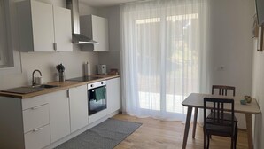 Una cocina moderna con armarios blancos, encimera de madera, horno empotrado y comedor con mesa y sillas.