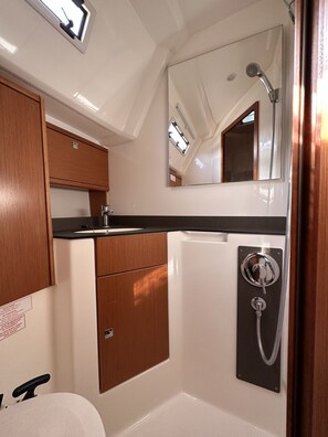 A compact bathroom with a sink, mirror, and shower. - Sun-Kissed Sailing Adventure in Zadar, Croatia (Drage)