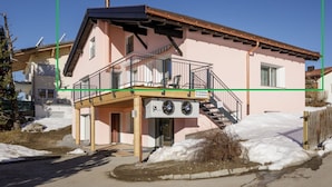 Un edificio di due piani con un balcone, una scala e un cartello che indica un'attività commerciale.